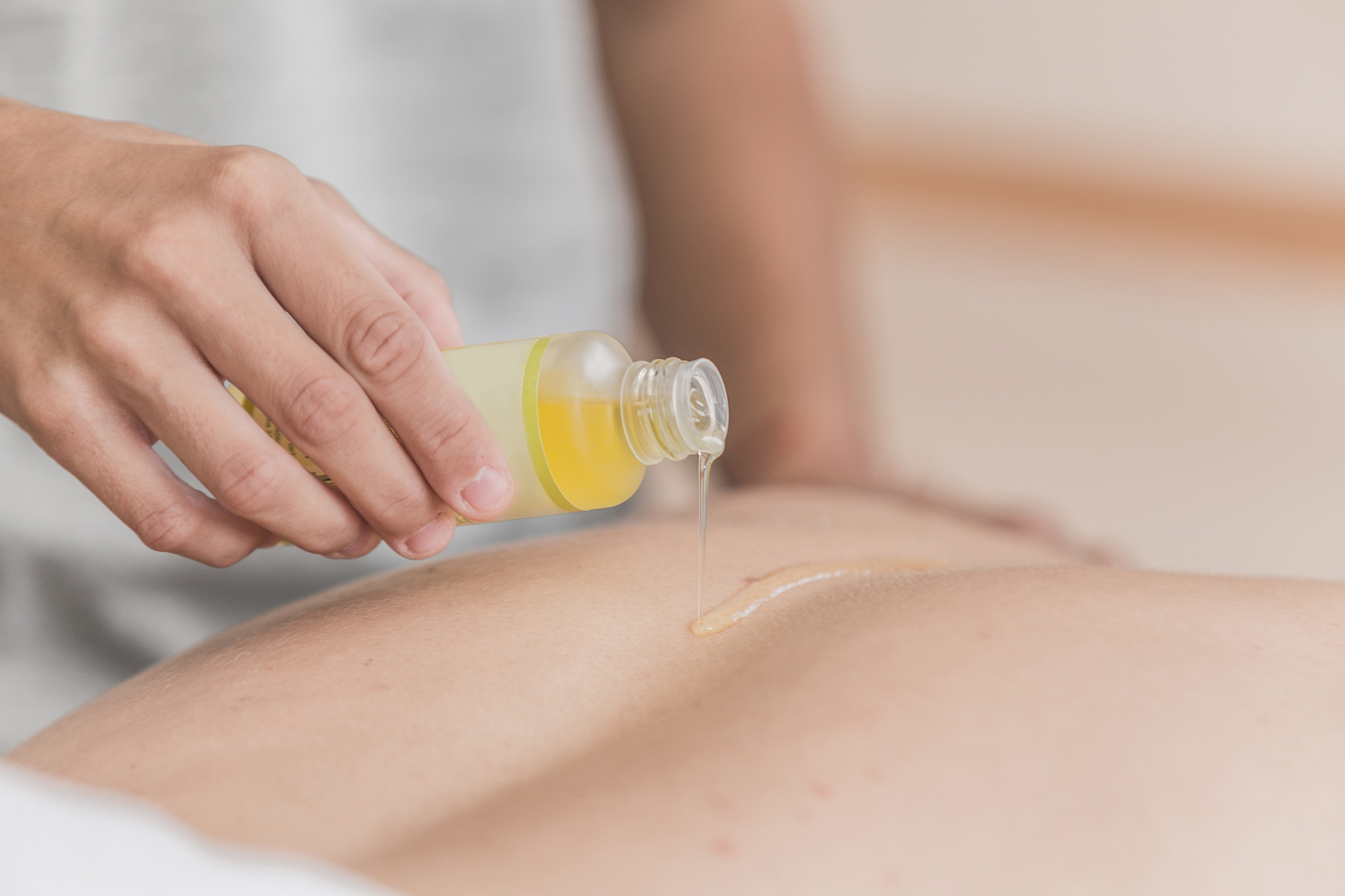 Masseuse pouring masage oil on the body