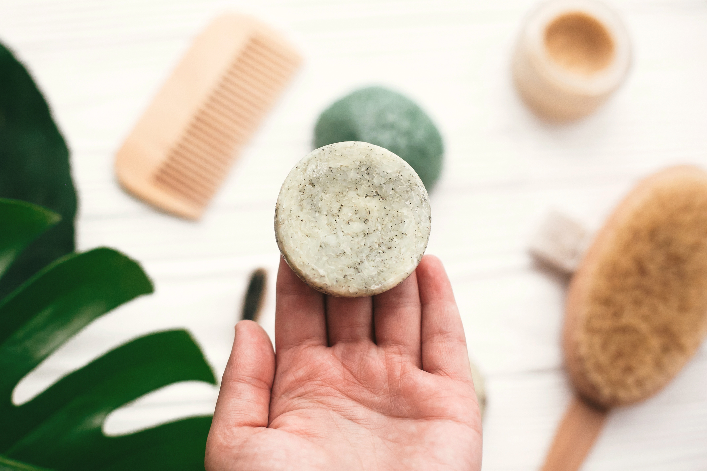 Hand Holding Natural Solid Shampoo Bar on Background of Bamboo B